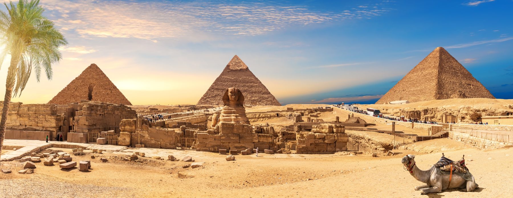 The Pyramids of Giza and the Sphinx across the desert at sunset
